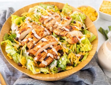 Barbecue Chicken Salad in a wooden bowl topped with barbecue creamy dressing.