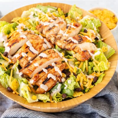 Barbecue Chicken Salad in a wooden bowl topped with barbecue creamy dressing.