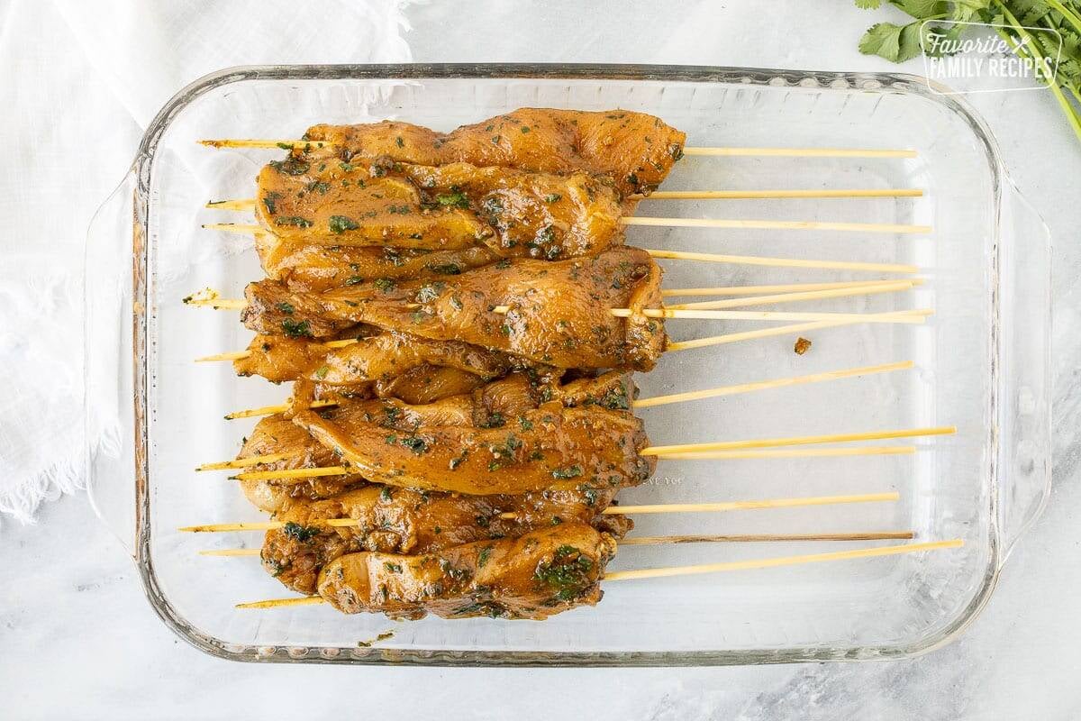 Thai Chicken on skewers in a glass pan.