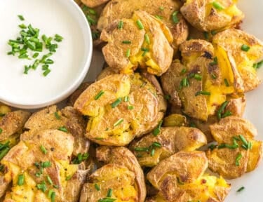 Smashed potatoes on a plate topped with chives