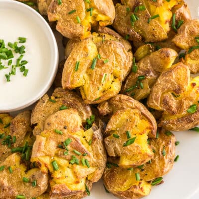 Smashed potatoes on a plate topped with chives