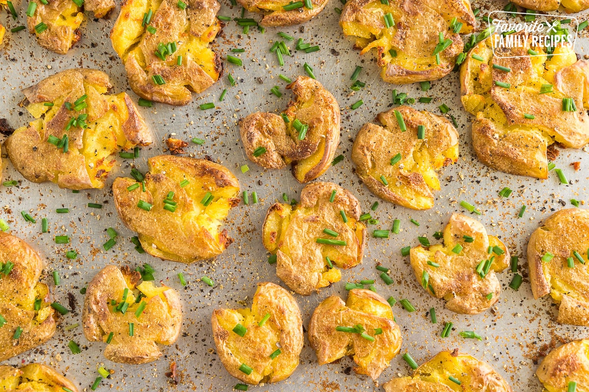 Smashed potatoes on a baking sheet topped with chives.