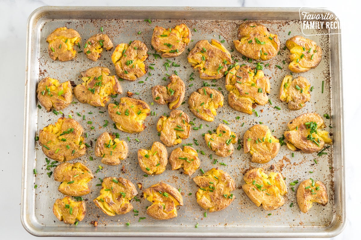 Smashed potatoes on a baking sheet topped with chives.