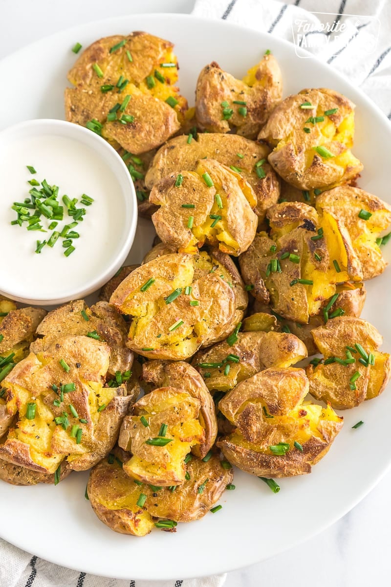 Smashed Potatoes are a perfect side dish for any dinner! They are crispy on the outside and fluffy on the inside. Serve with your favorite dip! Smashed potatoes on a plate topped with chives.