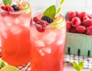 A Sparkling Berry Mojito Mocktail garnished with berries, lime, and mint