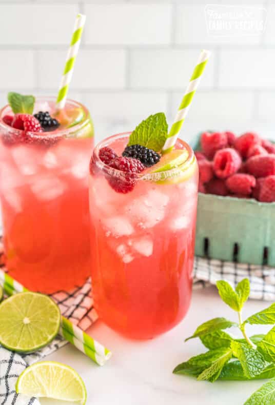 A Sparkling Berry Mojito Mocktail garnished with berries, lime, and mint