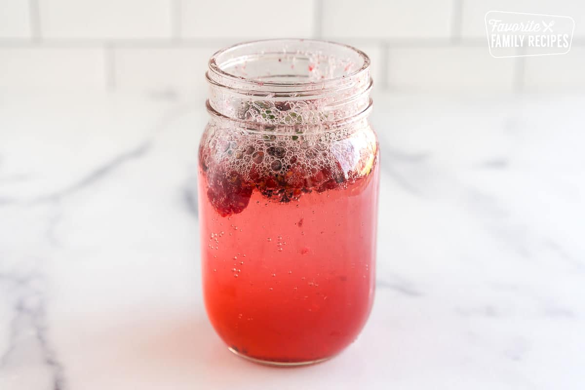 A mason jar with club soda and berries