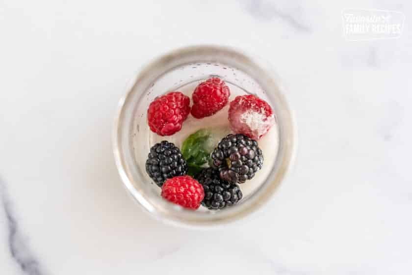A cup with raspberries, blackberries, mint, lime juice, and sugar