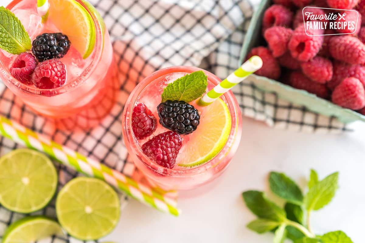 A Sparkling Berry Mojito Mocktail garnished with berries, lime, and mint.