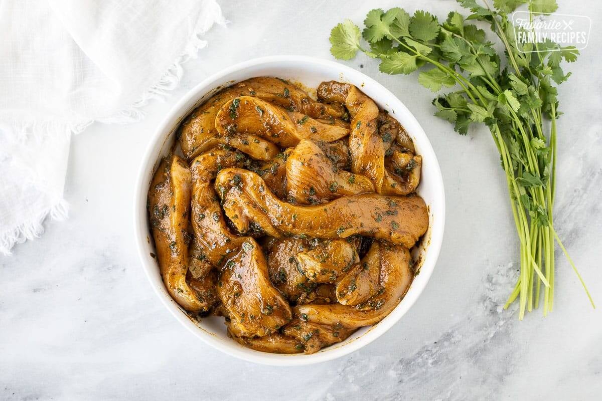 Thai chicken marinating in a white bowl.