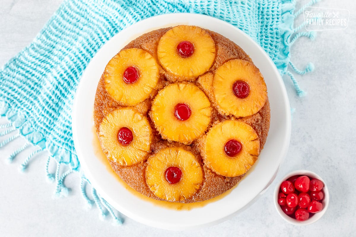 Pineapple Upside Down Cake with pineapple slices and cherries on top of a cake stand.
