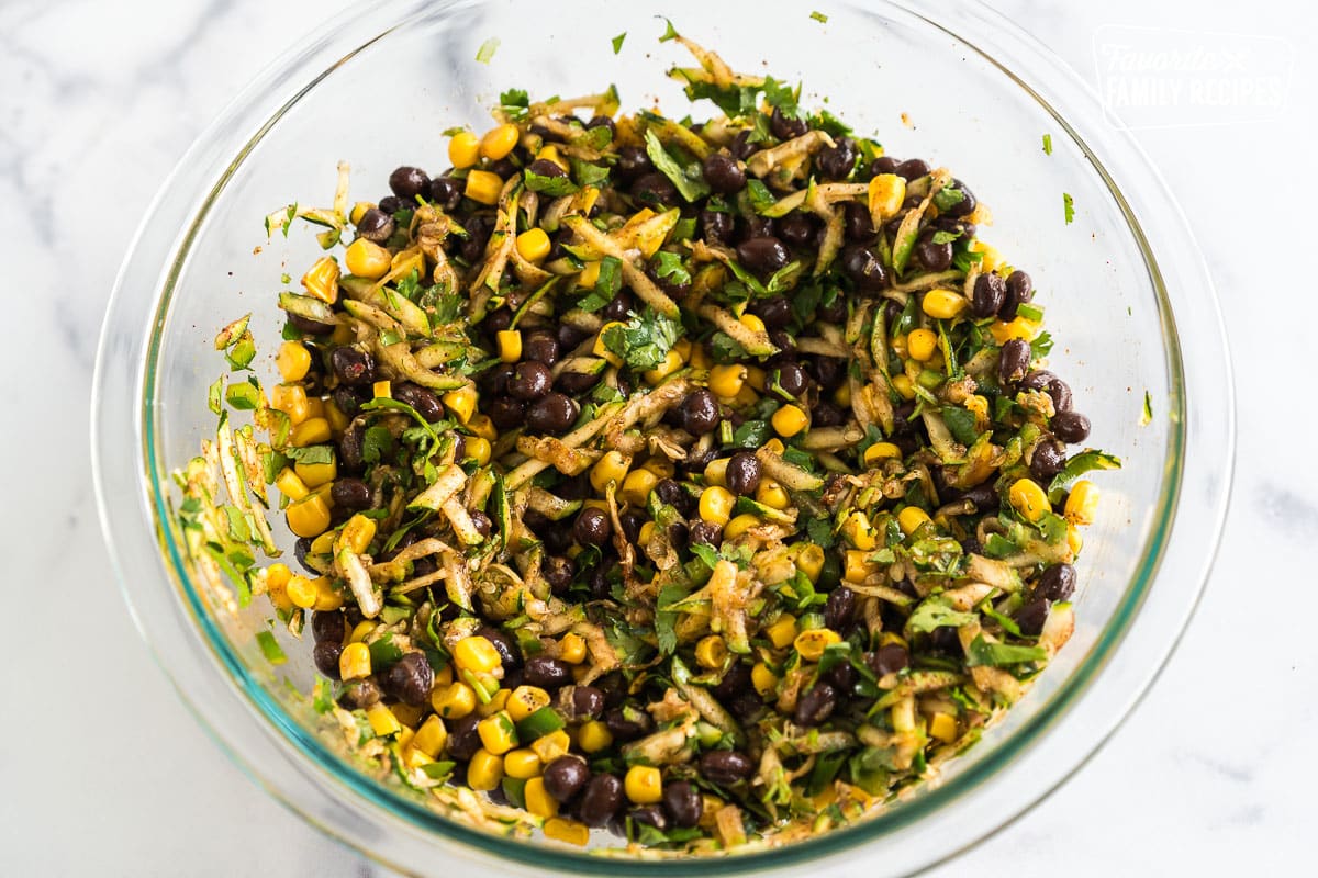 Black beans, corn, zucchini, and spices in a bowl.