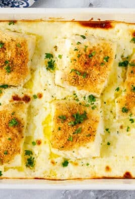 Baking dish with five pieces of Baked Cod in Cream Sauce garnished with parsley.