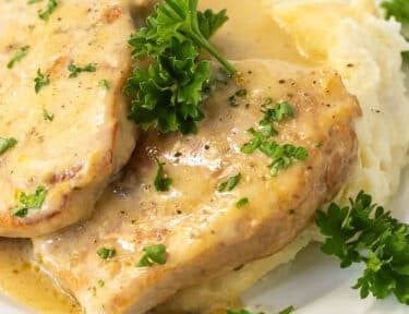Fork-tender pork chops with creamy homemade gravy on a plate, ready to serve.