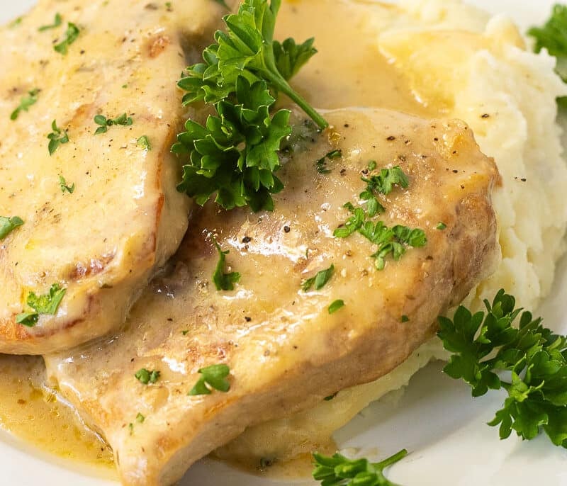 Fork-tender pork chops with creamy homemade gravy on a plate, ready to serve.