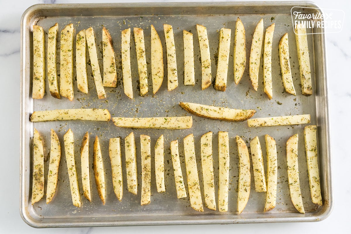 Cut and seasoned potatoes spread out on a baking sheet