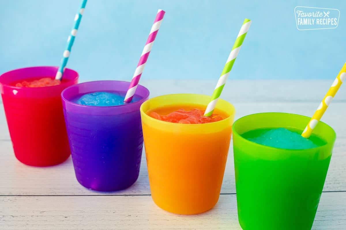 Four cups of lined up slushie with straws.