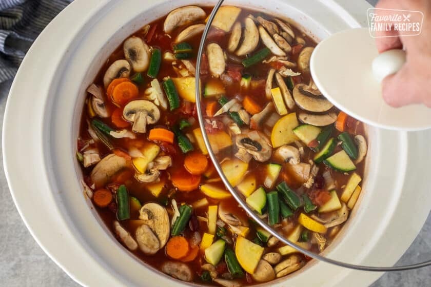 Placing a lid on a crock pot full of Weight Loss Magic Soup.