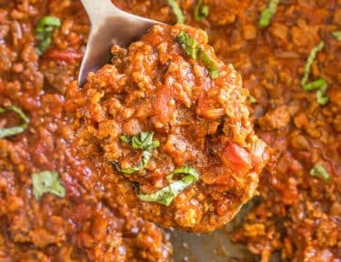 A scoop of meat sauce on a metal spoon