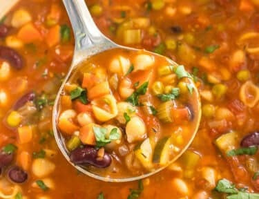 A ladleful of Minestrone soup from a pot