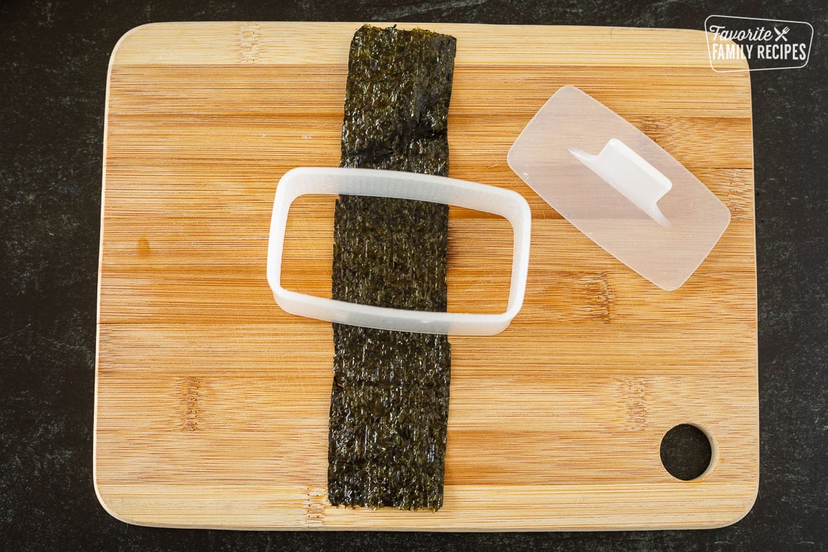 Cutting board with a strip of Nori and Spam Musubi mold.