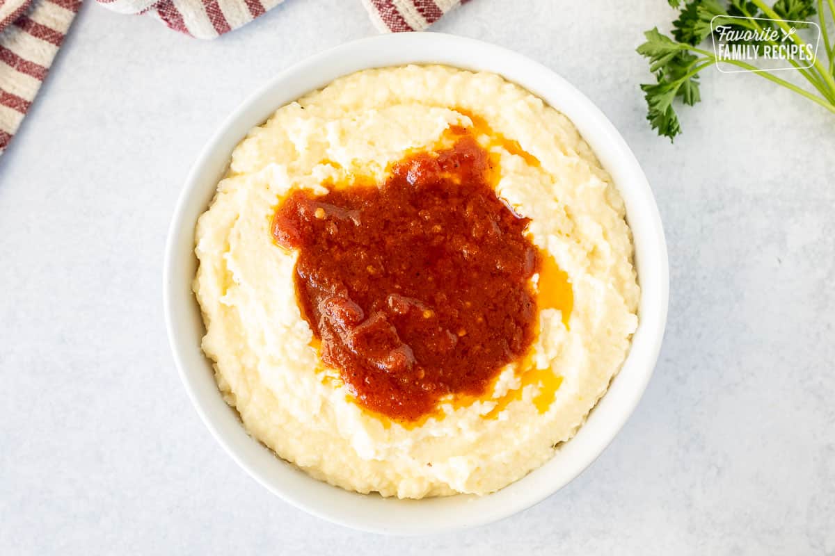 Bowl with cheesy grits and sauce in the middle.