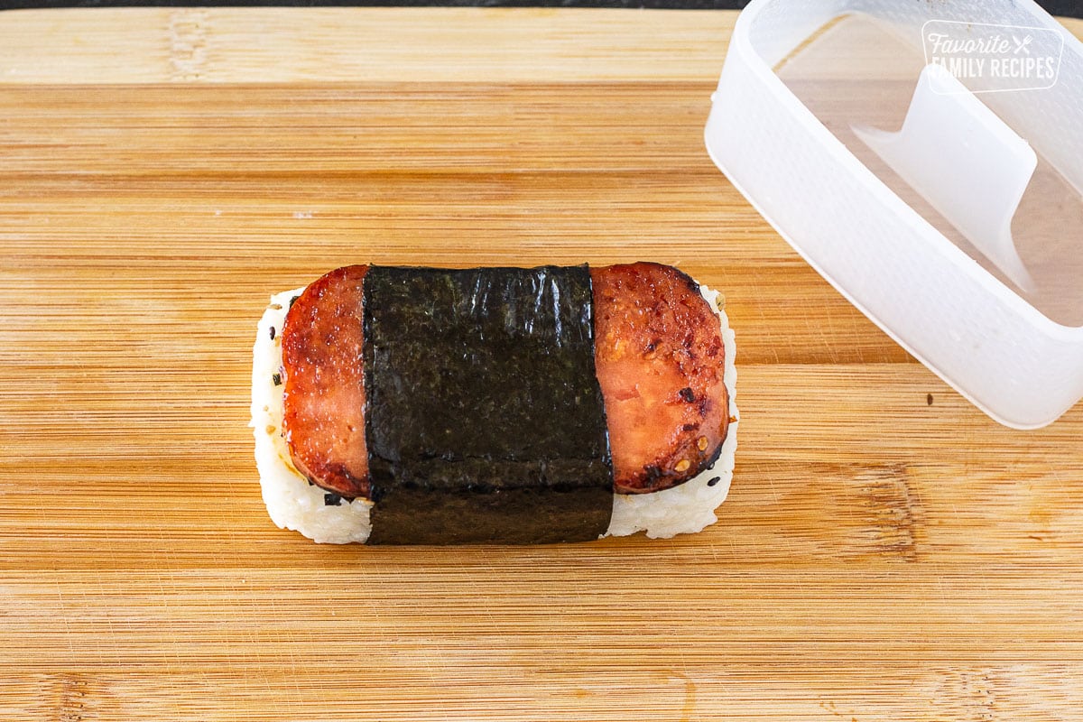Cutting board with constructed Spam musubi.