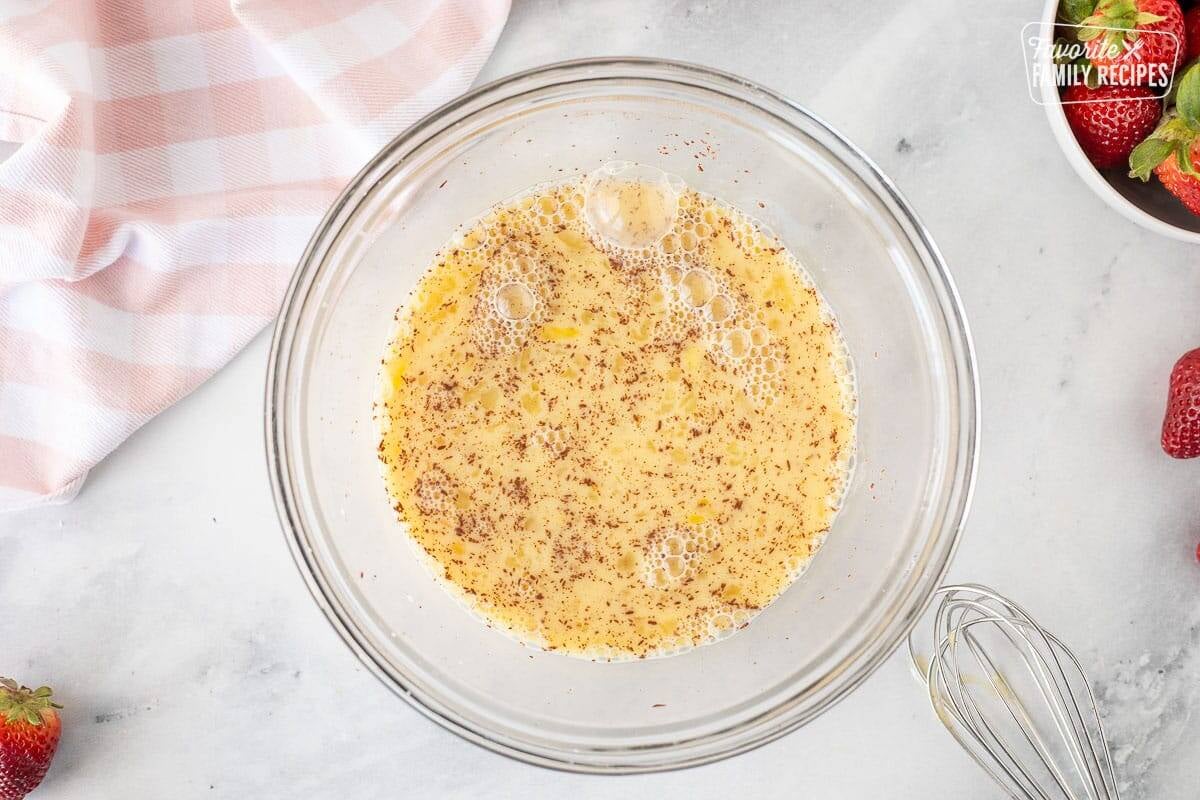 Mixing bowl with egg mixture and whisk on the side.