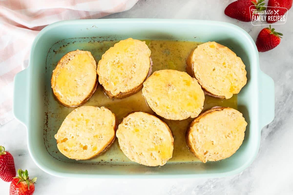 Baking dish with soaked Strawberry French Toast and melted butter on top.