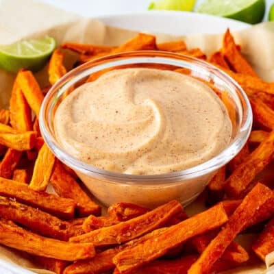 Plate of sweet potato fries with dipping sauce in the center.
