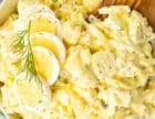 Wooden spoon resting in a bowl of Homemade Potato Salad.