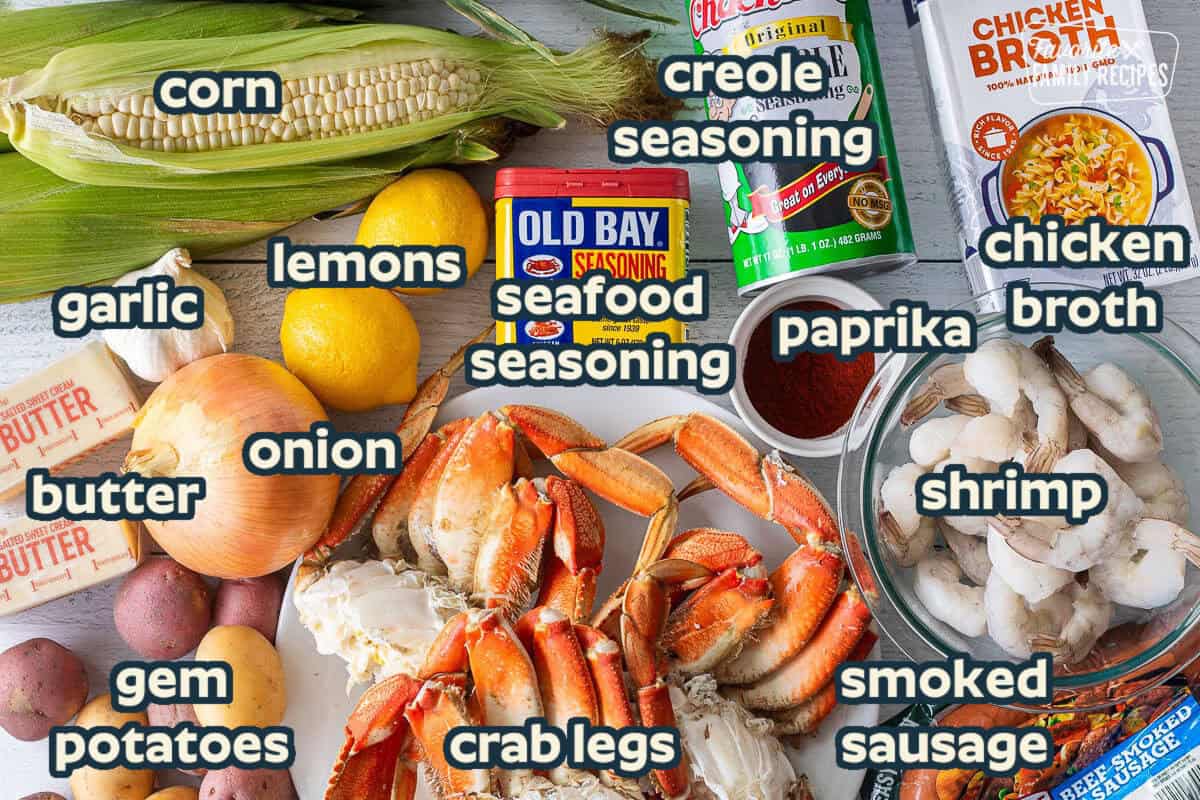 Ingredients to make Crab Boil including creole seasoning, chicken broth, Old Bay, lemons, corn on the cob, paprika, raw shrimp, beef smoked sausage, crab legs, potatoes, butter, onion and garlic.