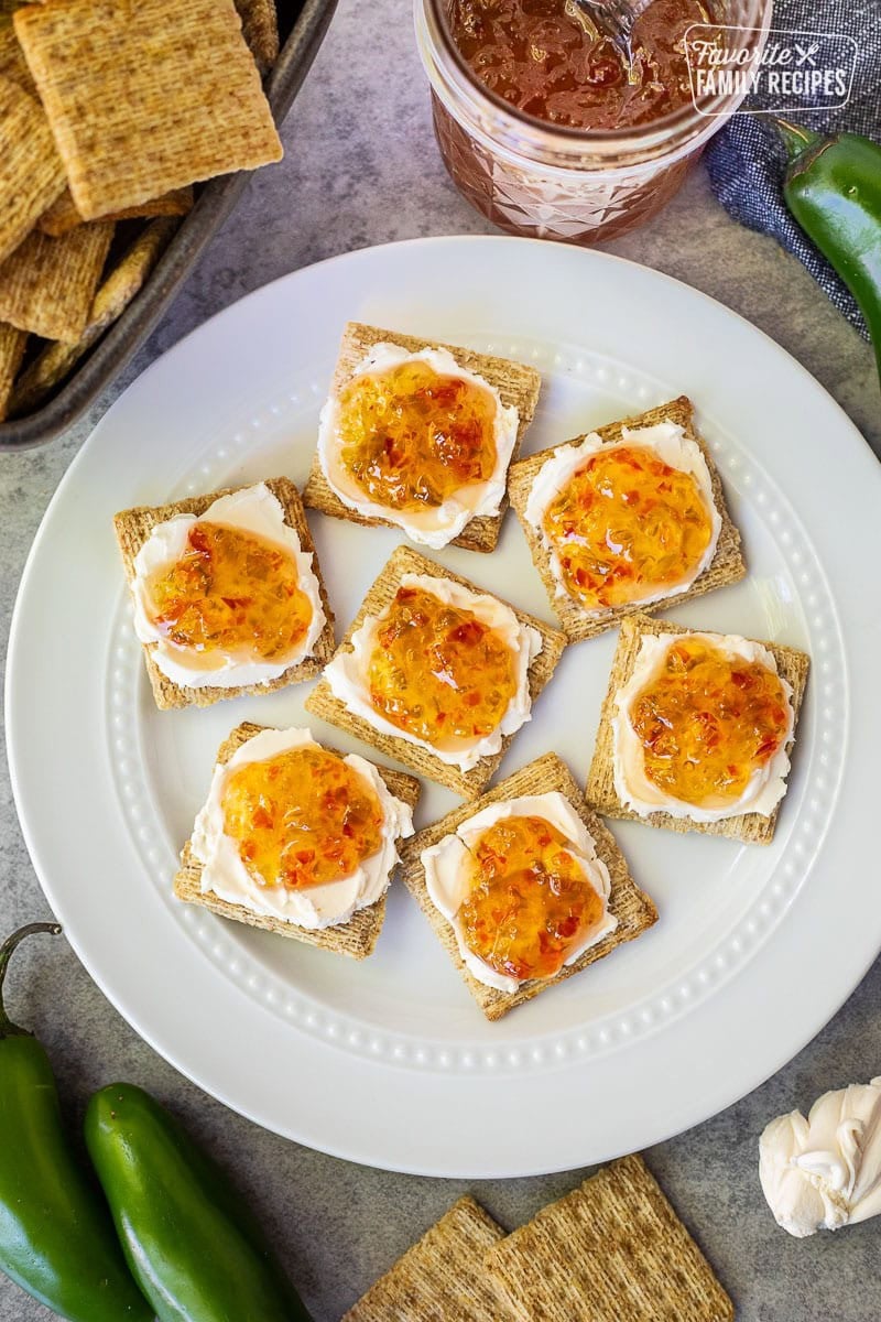 Plate with crackers spread with cream cheese and jalapeño pepper jelly.