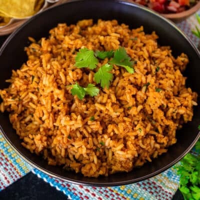 Cooked Mexican Rice side dish in a bowl topped with a sprig of cilantro.