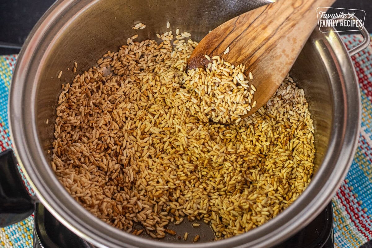 Golden rice with seasoning in a saucepan, the first step in making a homemade Mexican rice side dish.