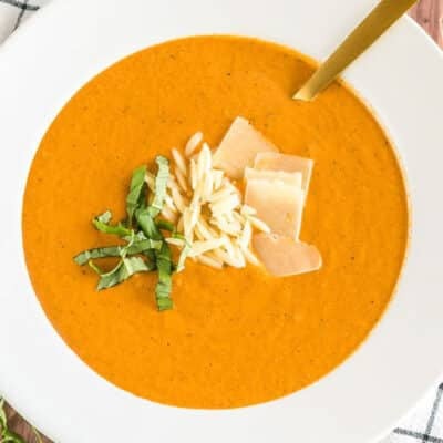 Zupas tomato basil soup in a white bowl with a gold spoon.