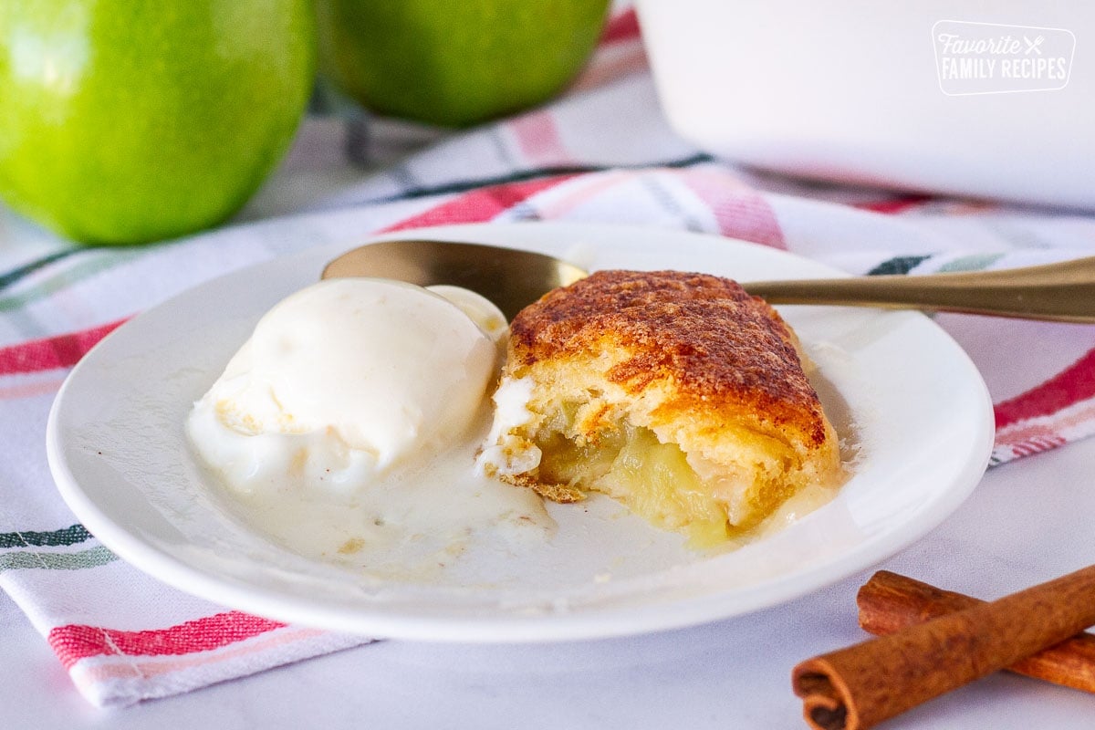 Cut open Apple Dumpling on a plate with a scoop of melty vanilla ice cream.