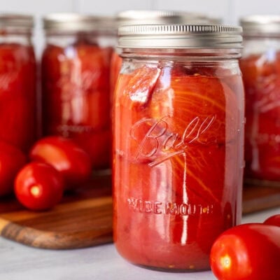 Canning jar with whole tomatoes. Roma tomatoes on the side.