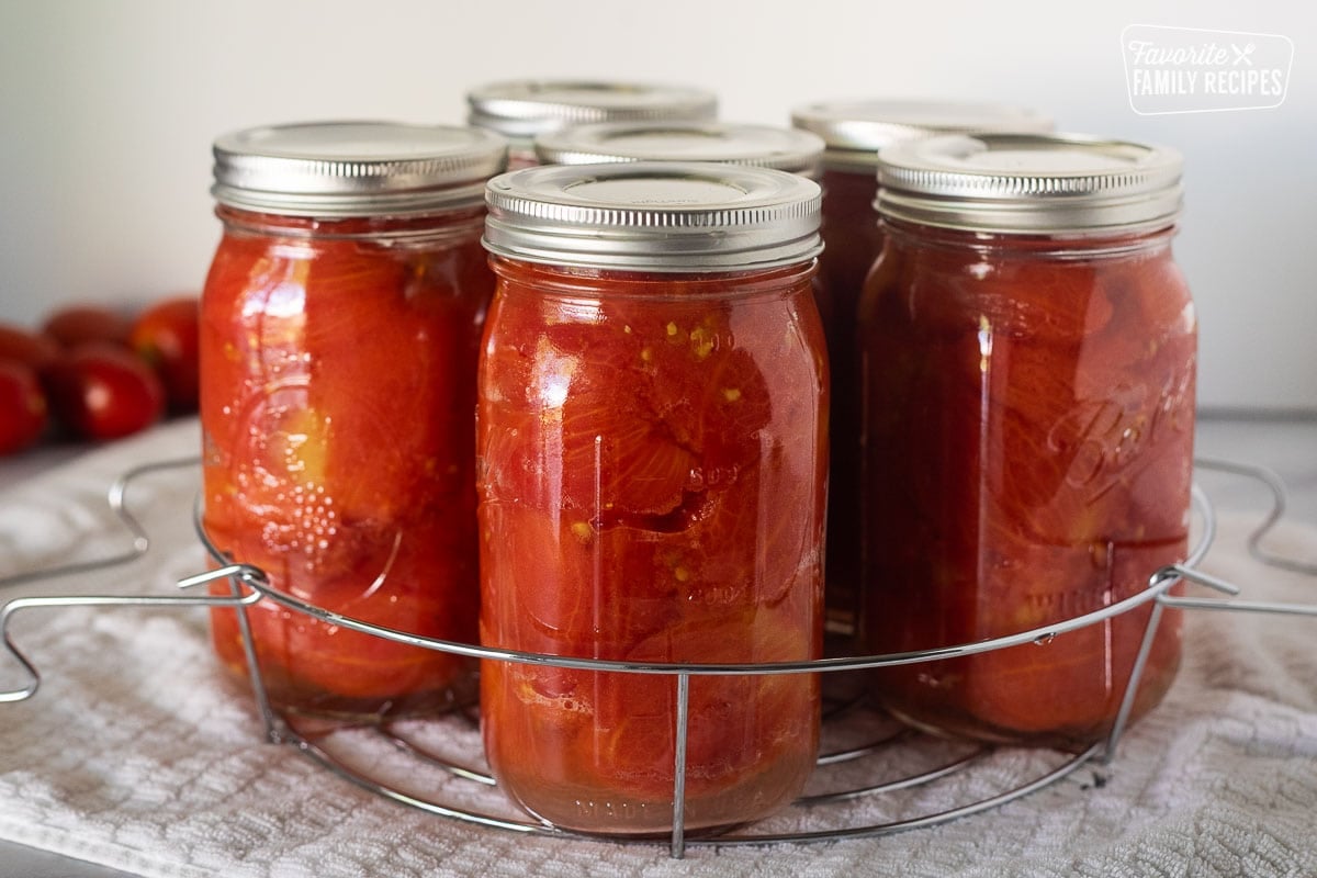 Canning rack with jars of whole tomatoes.