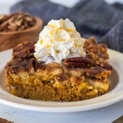 Slice of Pumpkin Cobbler with whipped cream and caramel drizzle on a plate.