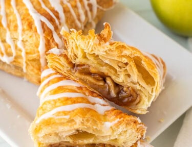 Apple Turnover cut in half with icing on a tray.