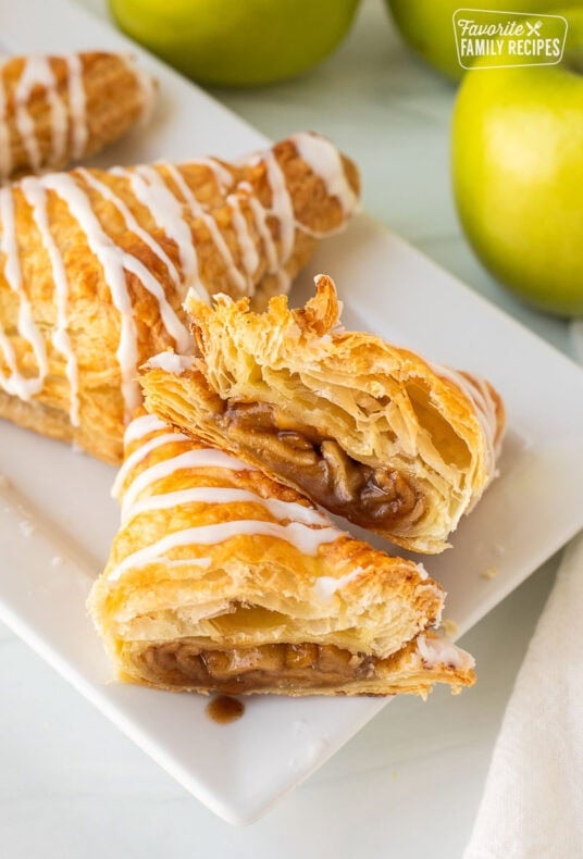 Apple Turnover cut in half with icing on a tray.