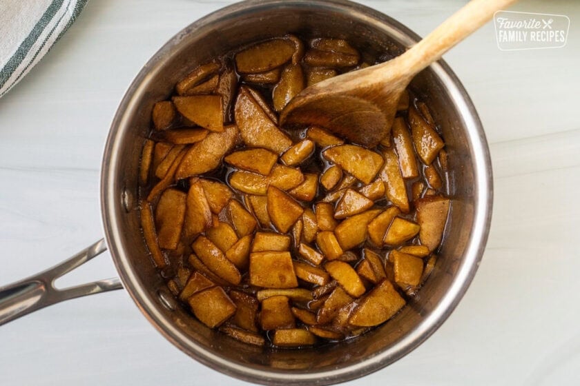 Cooked apples in a saucepan with a wooden spoon.