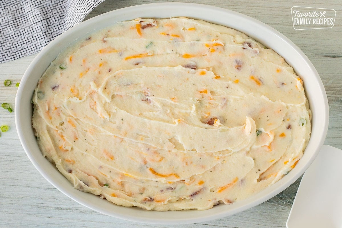 Baking dish with loaded mashed potato mixture. Spatula on the side.