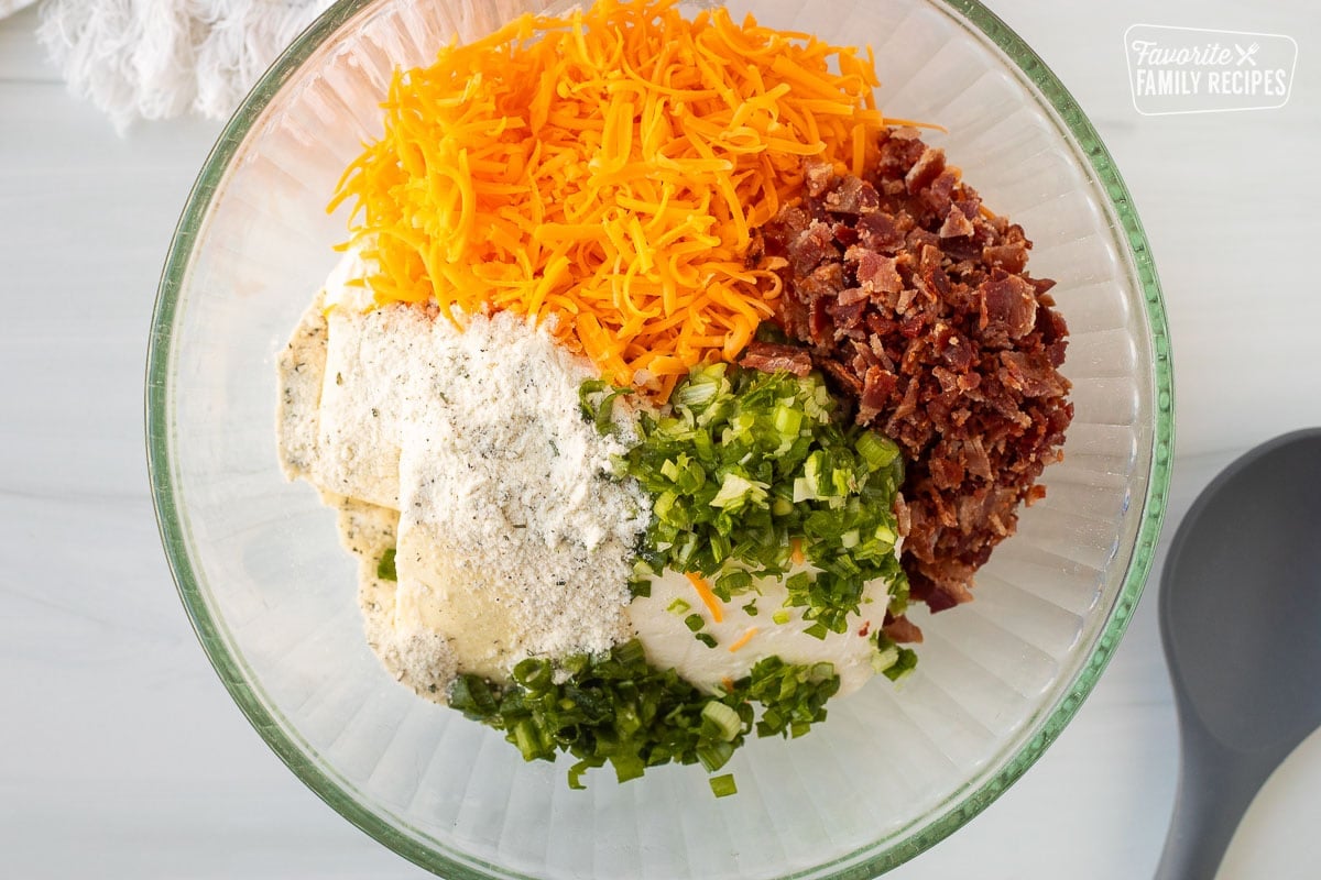 Glass bowl with cream cheese, sharp cheddar cheese, bacon, ranch seasoning packet and chopped green onions. Spoon on the side.