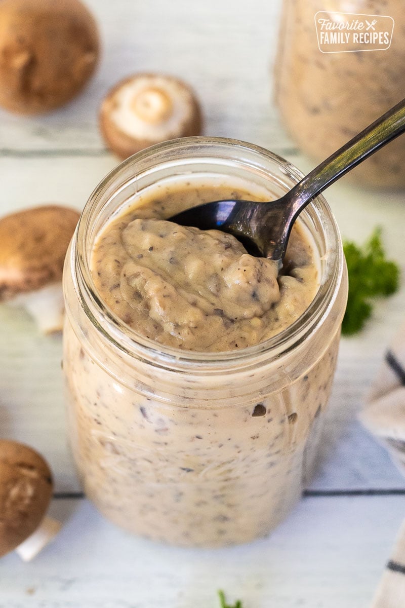 Spoon resting in a jar of Condensed Cream of Mushroom Soup.