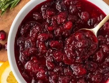 Bowl of orange cranberry sauce and a spoon.