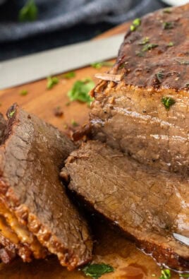 Fork in piece of oven roast beef on a cutting board.