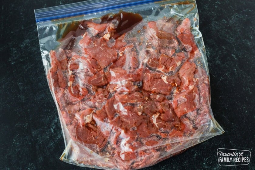 Sliced beef being marinated in a plastic bag
