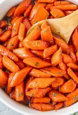 Bowl of candied carrots with a wooden spoon.